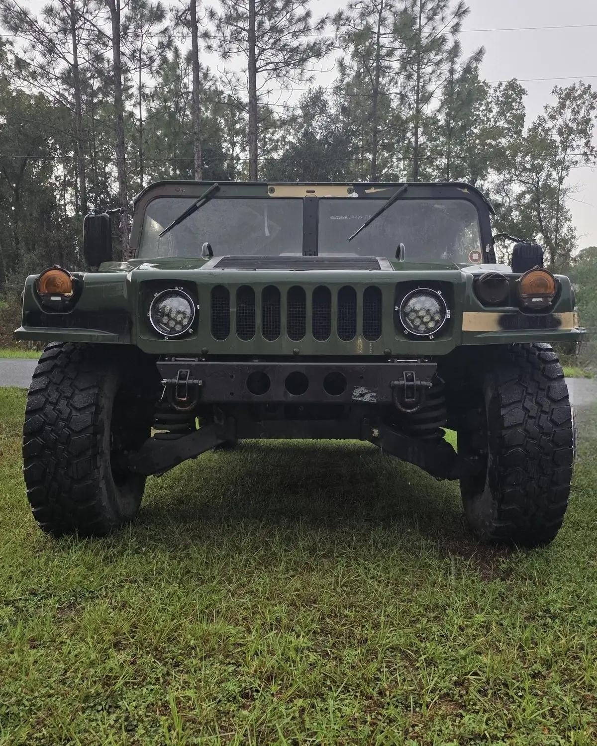 iFIXED HMMWV in olive green parked on wet grass in front of Florida pines